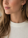 Frau trägt lange in Farbe gold Kettenohrringe mit geschwungenem Spiralstab – elegante Einfädler-Hängeohrringe in Gold, zarter Boho-Schmuck für besondere Anlässe